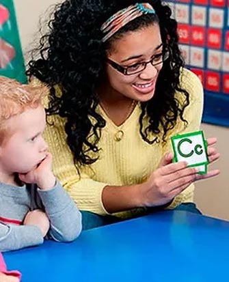 Women and child looking at alphabet flash cards