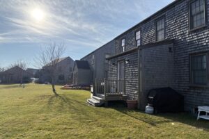 View of a lawn and the back of several cedar shingle house. 